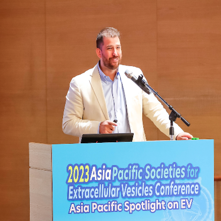 A man in a white jacket addressing an audience from a podium.