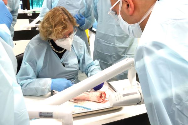 A team of medical professionals in scrubs and masks operating, with surgical tools and equipment visible.