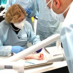 A team of medical professionals in scrubs and masks operating, with surgical tools and equipment visible.